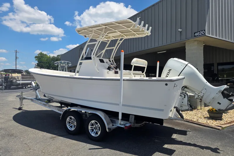 Slide: The Image of 2021 Vanquish 23 CC boat on trailer, parked outside a building under a clear sky. - 2