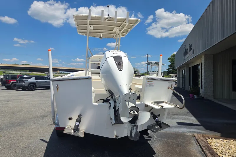 Slide: The Image of 2021 Vanquish 23 CC boat with outboard motor, parked outdoors under a clear blue sky. - 3