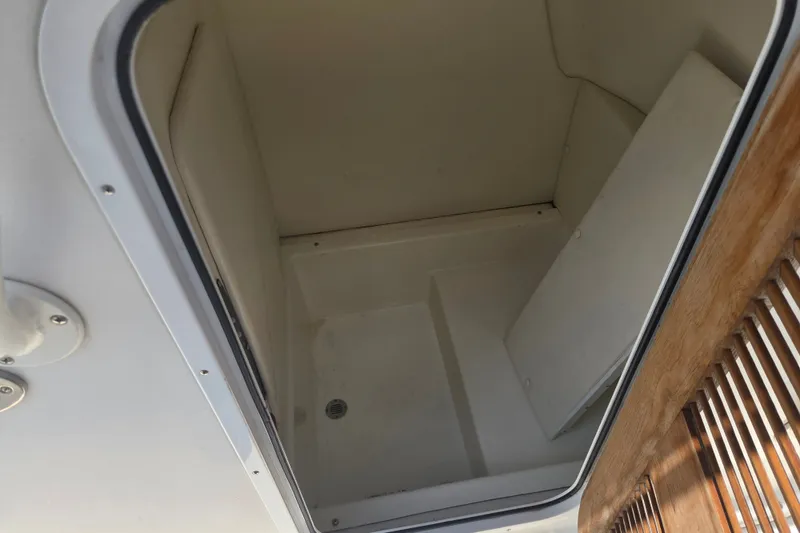 Slide: The Image of Interior storage compartment of a 2021 Vanquish 23 CC boat, featuring a wooden panel. - 11