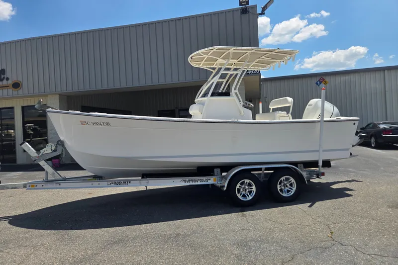 The Image of 2021 Vanquish 23 CC boat on trailer outside a building under a clear sky. - 0