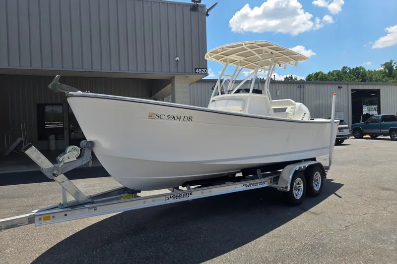 Slide: The Image of 2021 Vanquish 23 CC boat on trailer outside industrial building. - 1