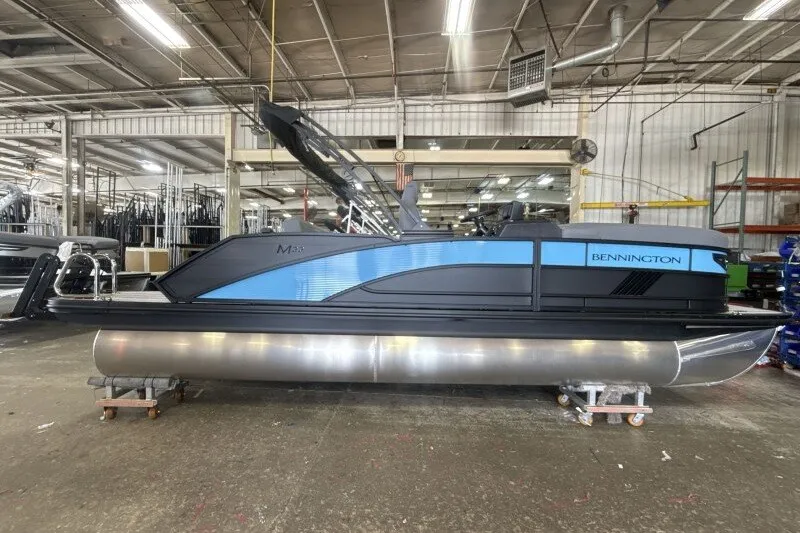 Slide: The Image of 2027 Bennington 22 M Swingback pontoon boat in a factory setting. - 1
