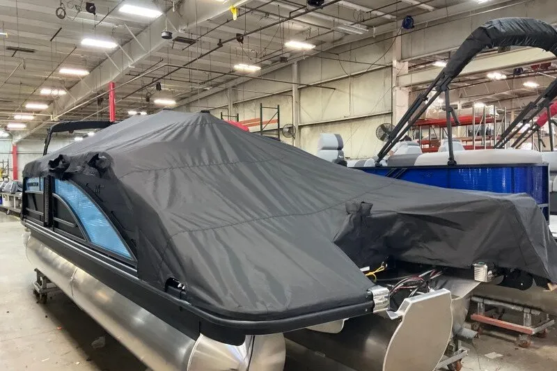 Slide: The Image of 2027 Bennington 22 M Swingback pontoon boat covered in a protective tarp in a warehouse. - 8