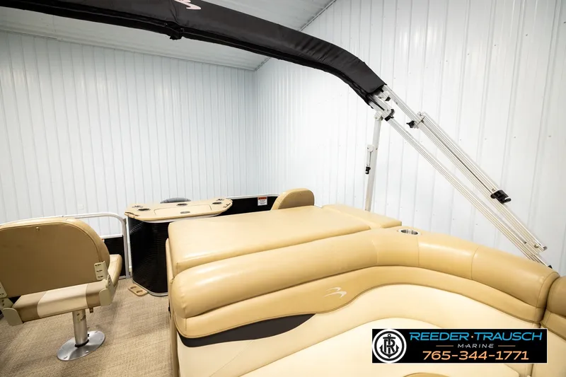 Slide: The Image of 2018 Bennington SX RF pontoon boat interior with beige seating and canopy in storage. - 25
