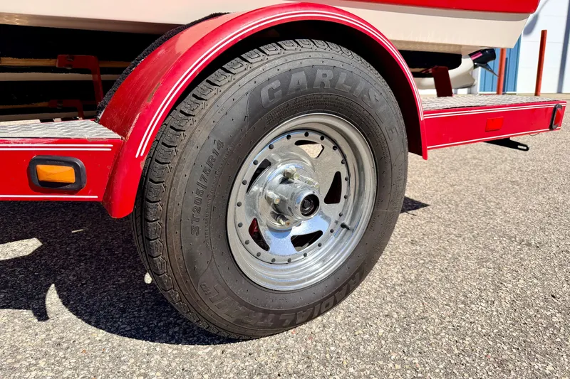 Slide: The Image of Red trailer wheel of 2003 Glastron GX 180 Ski & Fish boat on asphalt. - 61
