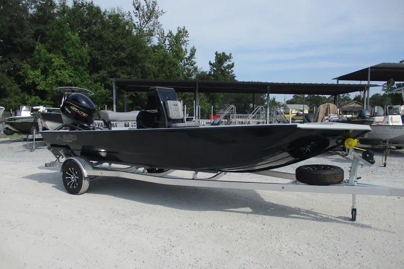 Slide: The Image of 2027 Avid 20 Rogue CC boat on trailer, parked outdoors with trees in background. - 2