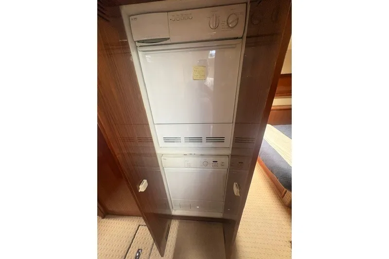 Slide: The Image of Laundry appliances inside 2007 Riviera 51 Enclosed Flybridge yacht, featuring a compact washer and dryer. - 33
