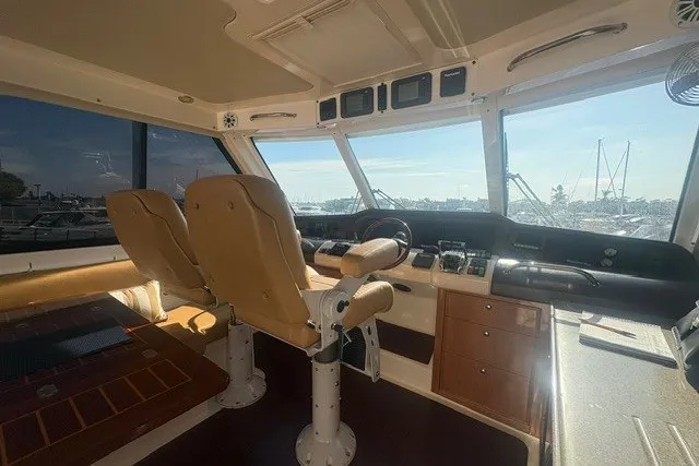 Slide: The Image of Interior of 2007 Riviera 51 Enclosed Flybridge with helm and seating, overlooking marina. - 15