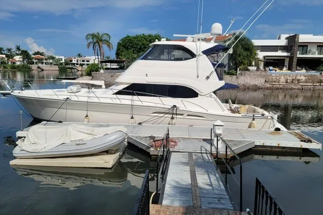 The Image of 2007 Riviera 51 Enclosed Flybridge yacht docked in a serene marina setting. - 1