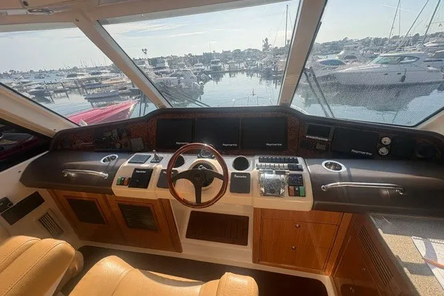 Slide: The Image of 2007 Riviera 51 Enclosed Flybridge helm with marina view, featuring navigation controls and leather seating. - 20
