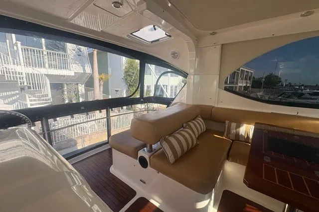 Slide: The Image of 2007 Riviera 51 Enclosed Flybridge interior with beige seating and striped cushions. - 17