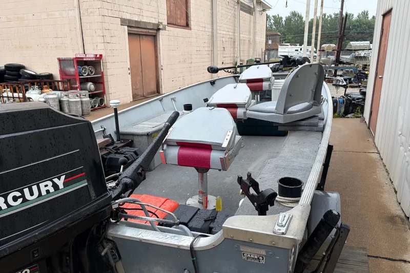 Slide: The Image of 1989 Lund 16 Pike SS boat with Mercury outboard motor, parked outdoors near a building. - 16