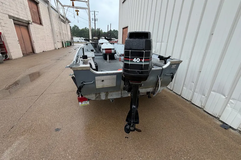 Slide: The Image of 1989 Lund 16 Pike SS boat with 40 HP outboard motor, parked outdoors. - 14