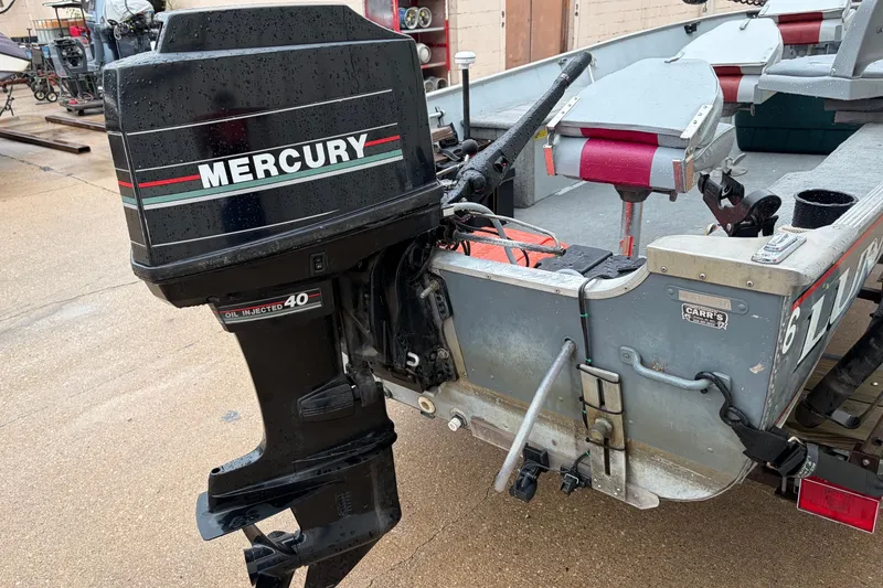 Slide: The Image of 1989 Lund 16 Pike SS boat with Mercury outboard motor, parked on a wet surface. - 15