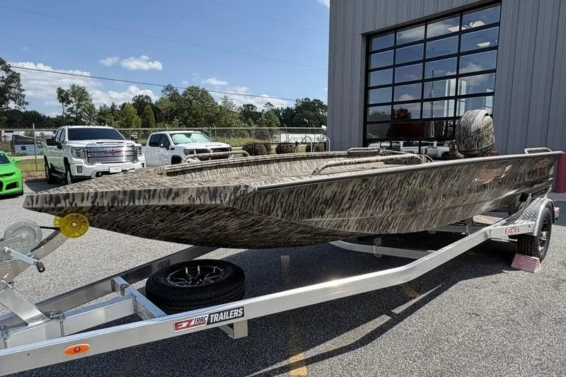 Slide: The Image of 2027 Excel 183 Tomahawk boat on trailer, parked outside a building. - 1