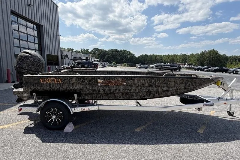 Slide: The Image of 2027 Excel 183 Tomahawk boat on trailer, parked outdoors under a partly cloudy sky. - 12