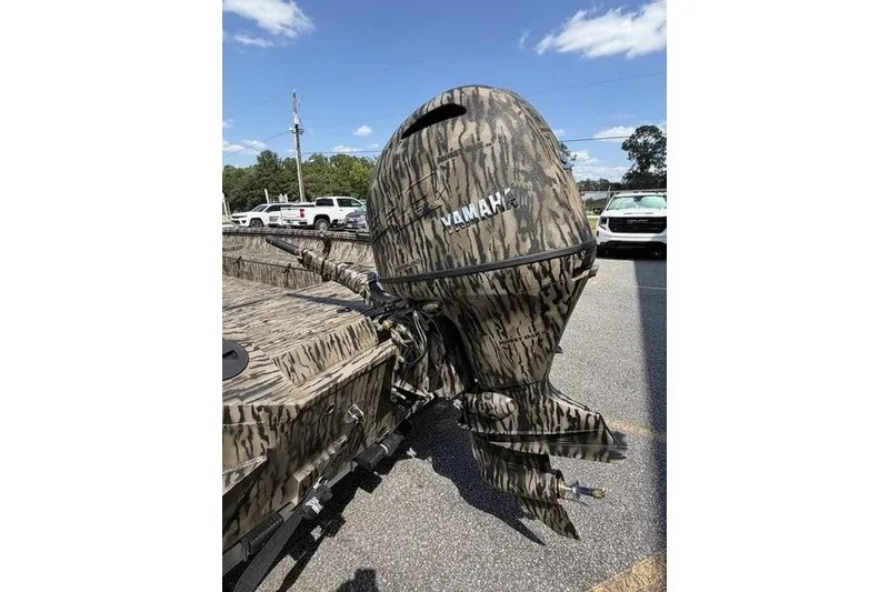 Slide: The Image of Camouflage-patterned Yamaha outboard motor on 2027 Excel 183 Tomahawk boat, parked outdoors. - 6