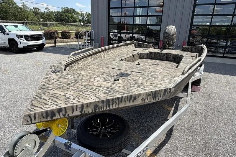 Slide: The Image of 2027 Excel 183 Tomahawk boat with camouflage design on a trailer, parked outdoors. - 13