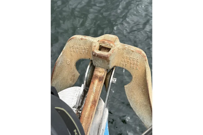 Slide: The Image of Rusty steel anchor on a Spencer 53 boat, 1974 model, over water. - 60