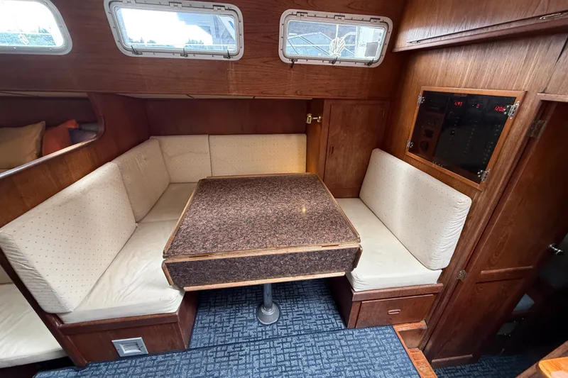 Slide: The Image of Cozy 1974 Spencer 53 yacht interior with cushioned seating and wooden table. - 14