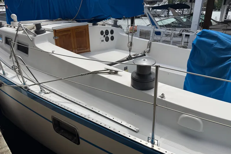 Slide: The Image of 1974 Spencer 53 sailboat deck with winches and blue cover in marina setting. - 3