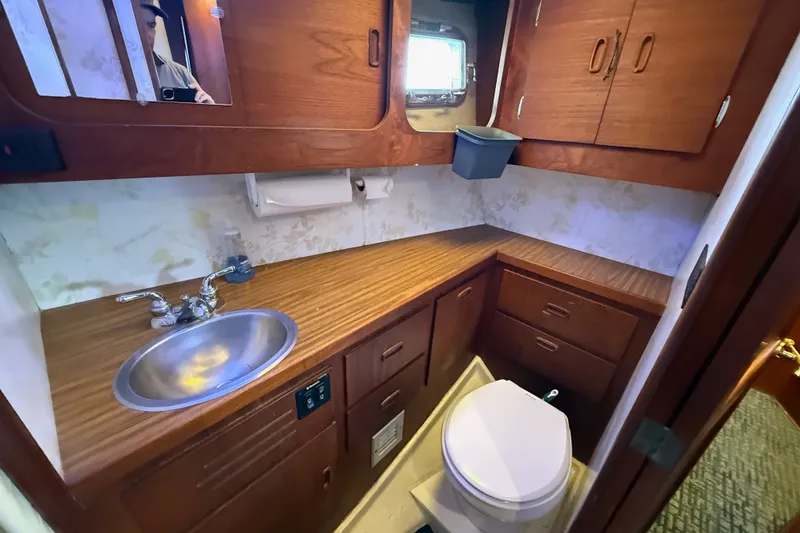 Slide: The Image of 1974 Spencer 53 yacht bathroom with wooden cabinets, sink, and toilet. - 23