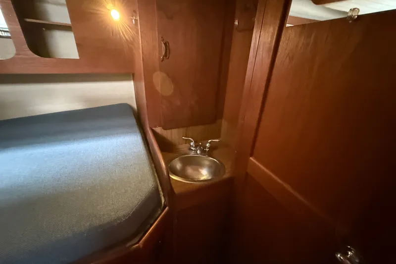 Slide: The Image of Cozy wooden interior of a 1974 Spencer 53 boat with a small sink and bed. - 30