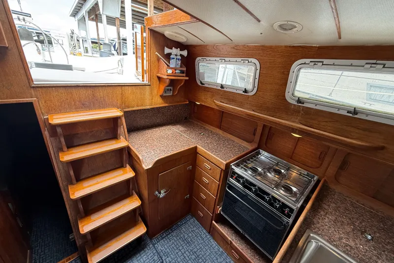 Slide: The Image of 1974 Spencer 53 yacht interior with wooden cabinetry, stairs, and kitchen area. - 10