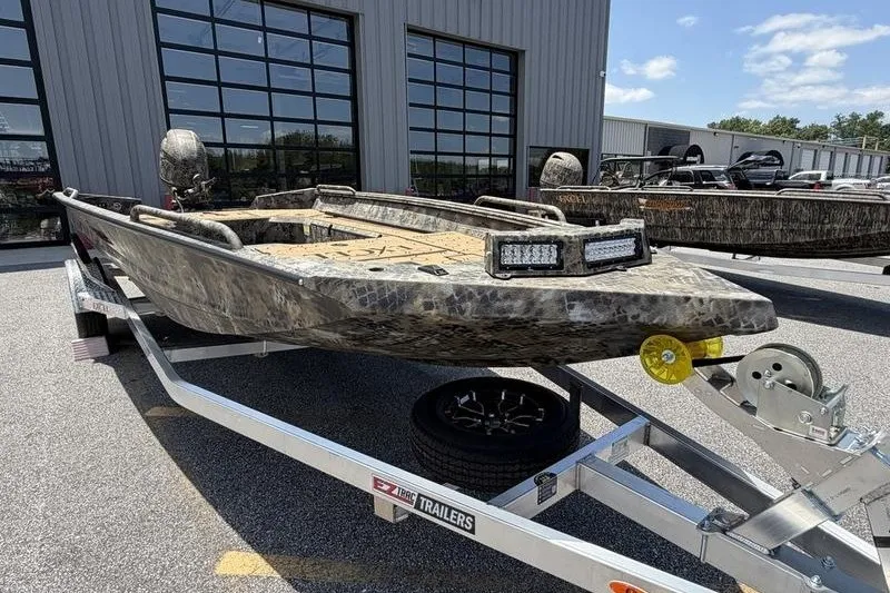 Slide: The Image of 2027 Excel 183 Tomahawk boat on trailer, parked outside industrial building. - 4