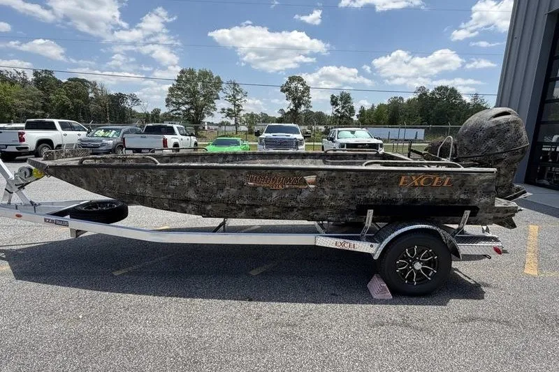 Slide: The Image of 2027 Excel 183 Tomahawk boat on trailer, parked outdoors under a sunny sky. - 21