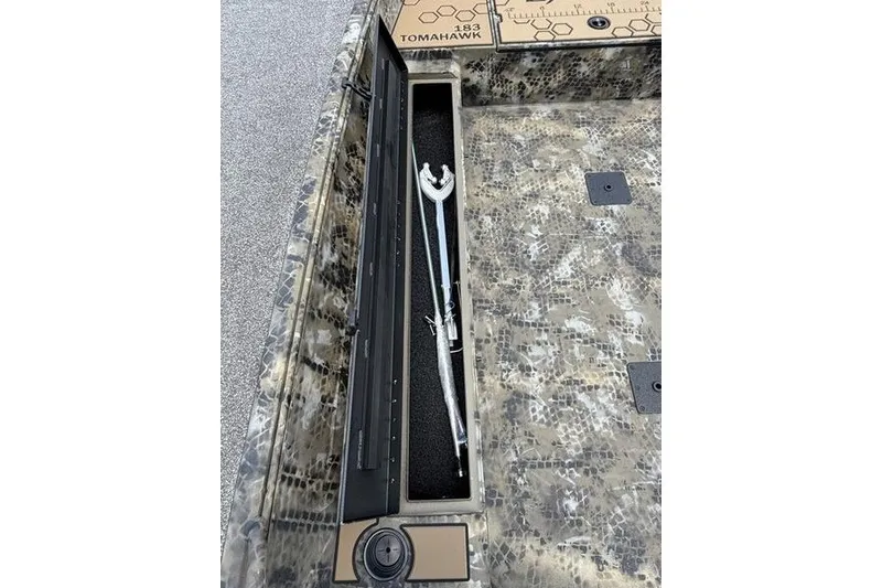Slide: The Image of Storage compartment in 2027 Excel 183 Tomahawk boat with camouflage design and fishing rod holder. - 12