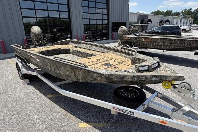 Slide: The Image of 2027 Excel 183 Tomahawk boat on trailer, camo design, parked outside a building. - 5