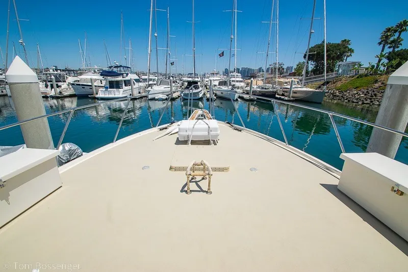 Slide: The Image of 1987 Hatteras 52 Convertible yacht docked in a marina, surrounded by sailboats. - 54