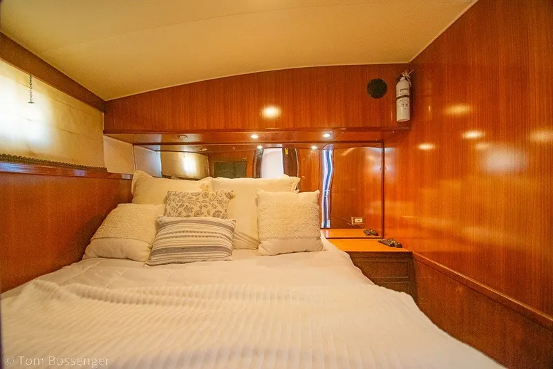Slide: The Image of Cozy bedroom interior of 1987 Hatteras 52 Convertible yacht with wood paneling and plush bedding. - 24