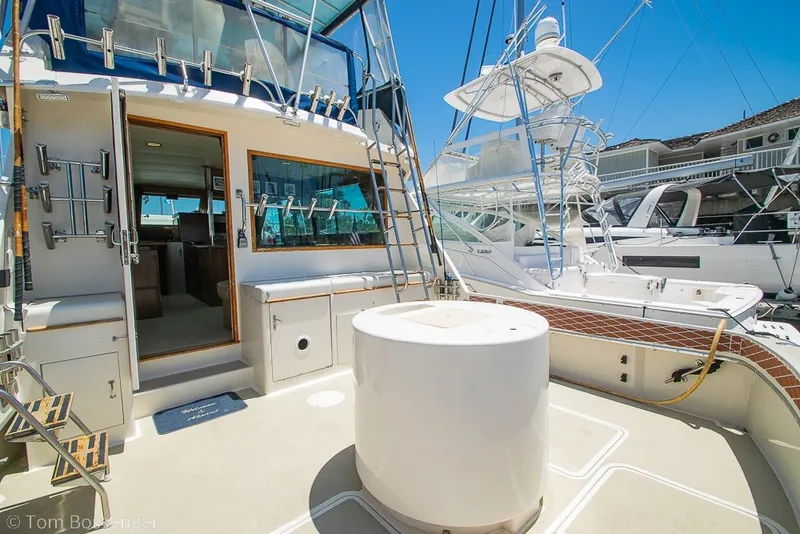 Slide: The Image of 1987 Hatteras 52 Convertible yacht deck with fishing equipment and marina view. - 37