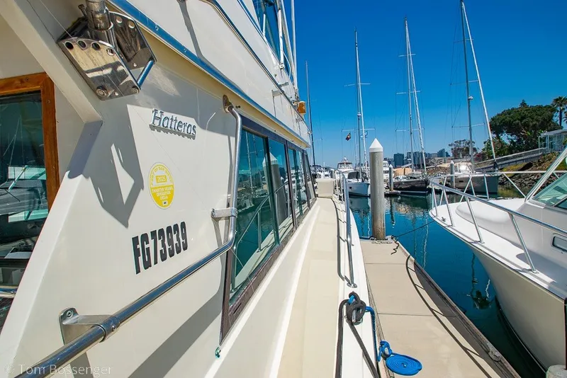 Slide: The Image of 1987 Hatteras 52 Convertible yacht docked at marina under clear blue sky. - 52