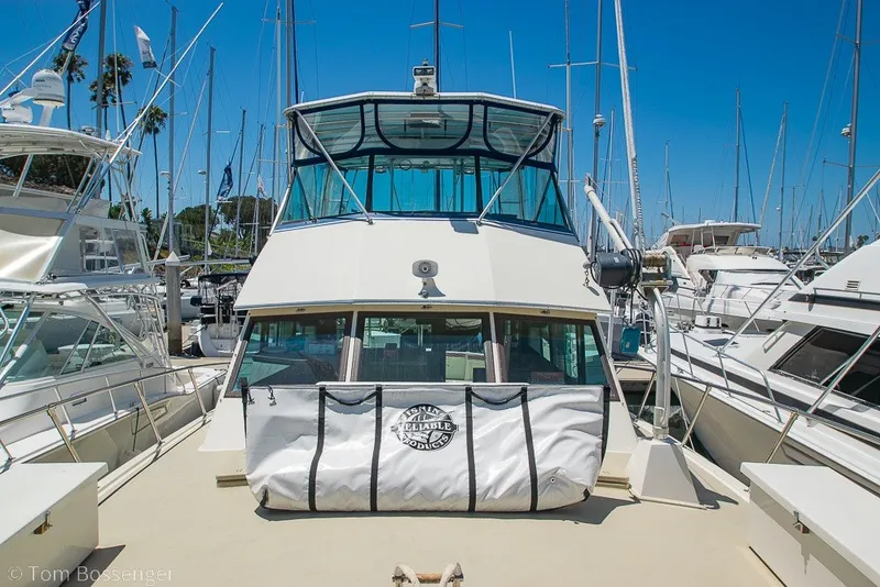 Slide: The Image of 1987 Hatteras 52 Convertible yacht docked in a marina under clear blue skies. - 57