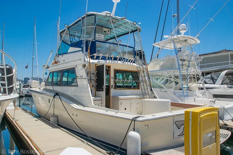 The Image of 1987 Hatteras 52 Convertible yacht docked at marina under clear blue sky. - 0