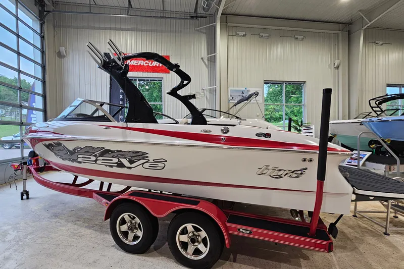 Slide: The Image of 2010 Tigé 22Ve boat on red trailer in showroom, side view. - 2