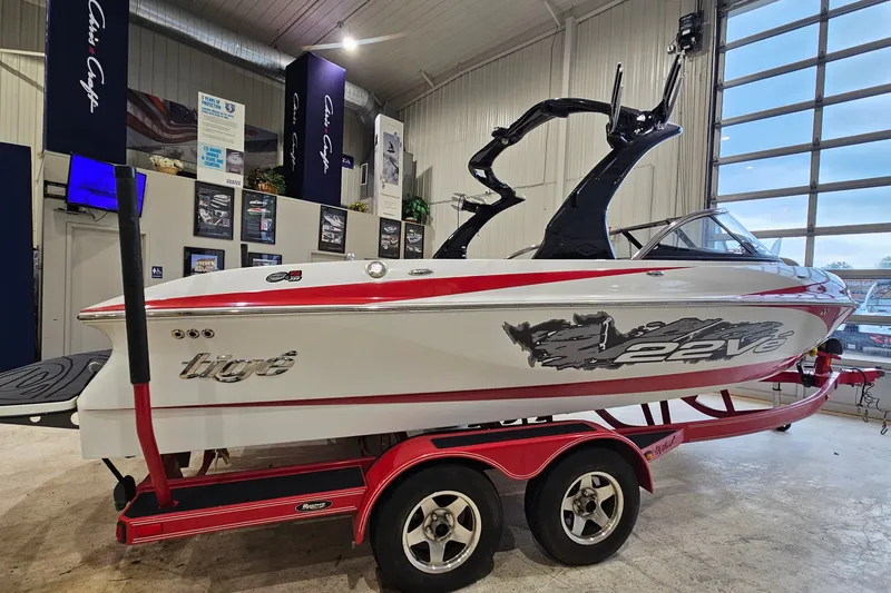 Slide: The Image of 2010 Tigé 22Ve boat on red trailer in showroom, side view. - 3