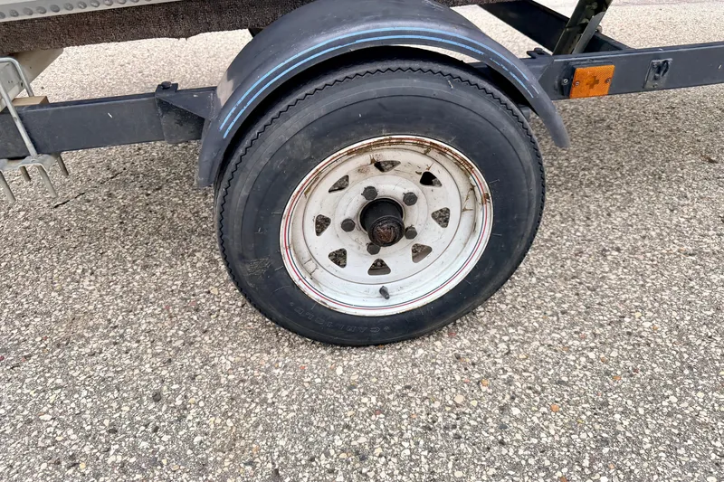Slide: The Image of Trailer wheel of a 1994 Tracker Guide V-14 Riveted Deep V on asphalt. - 43