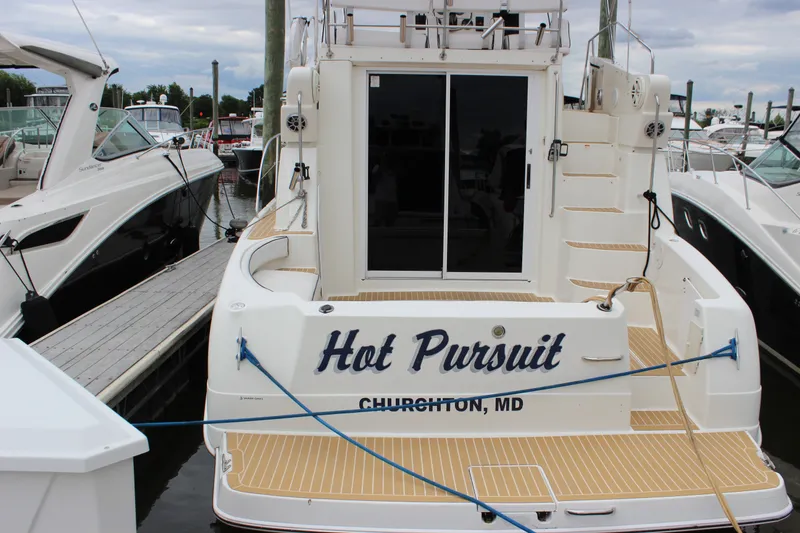 Slide: The Image of 1997 Silverton 351 Sedan yacht named "Hot Pursuit" docked at a marina. - 76