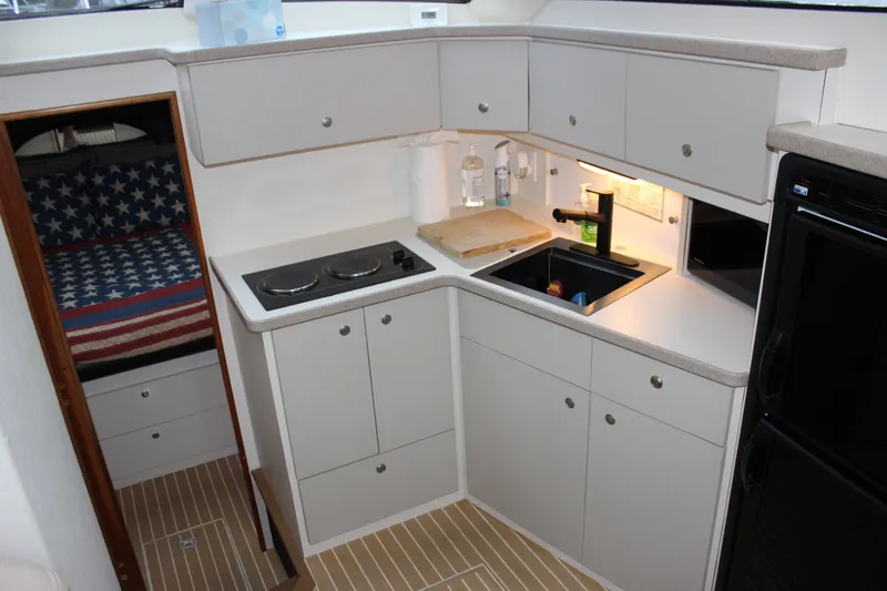 Slide: The Image of Compact kitchen area in a 1997 Silverton 351 Sedan yacht, featuring stove and sink. - 33