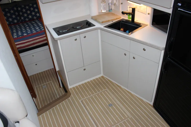 Slide: The Image of 1997 Silverton 351 Sedan yacht interior kitchen with stove, sink, and American flag bedding. - 32