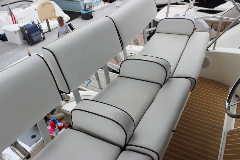 Slide: The Image of 1997 Silverton 351 Sedan boat interior with white cushioned seating and wooden flooring. - 15