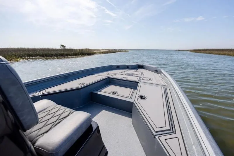 Slide: The Image of 2027 Excel 220 Bay Pro Elite boat on calm water, featuring spacious deck and seating. - 25