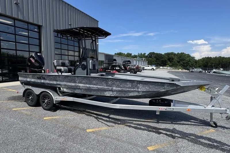 The Image of 2027 Excel 220 Bay Pro Elite boat on trailer, parked outside a warehouse. - 0