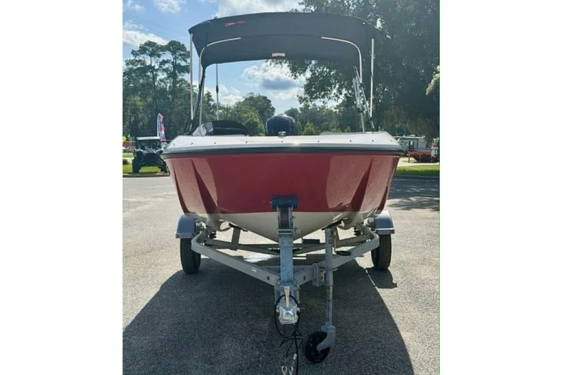 Slide: The Image of 2021 Bayliner Element E16 boat on trailer, red hull, parked outdoors. - 2