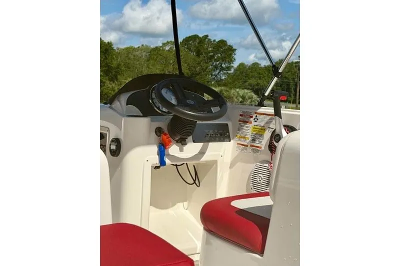 Slide: The Image of 2021 Bayliner Element E16 boat cockpit with steering wheel and red seating. - 9