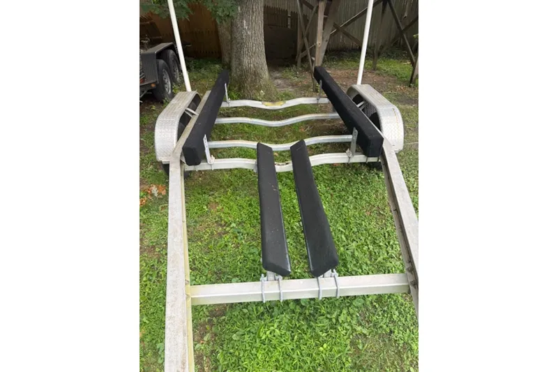 Slide: The Image of Boat trailer for 2023 NorthCoast 215 HT on grass, featuring padded supports. - 26